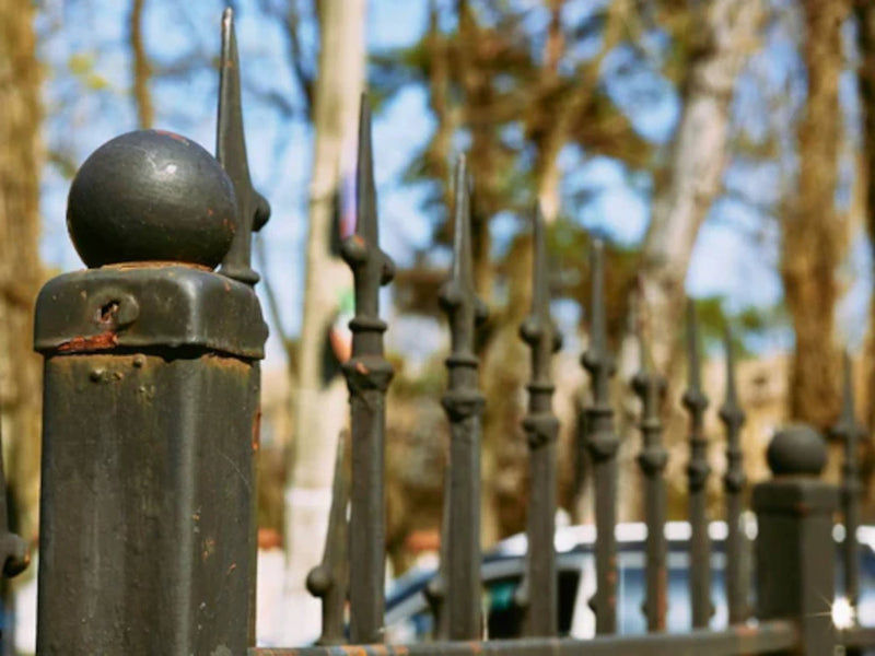 rusting and corroding wrought iron railing in need of maintenance with trees in background