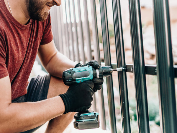 Man Fixing Metal Fence Panels with Drill